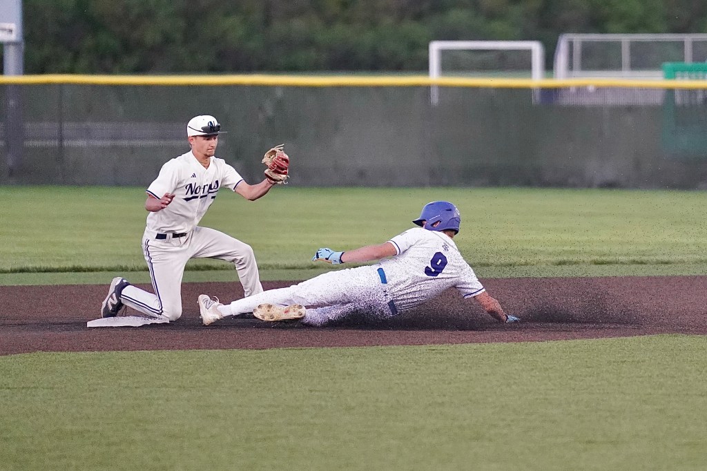 A baseball player in white uniform slides into second base while a fielder in dark uniform prepares to catch the ball.