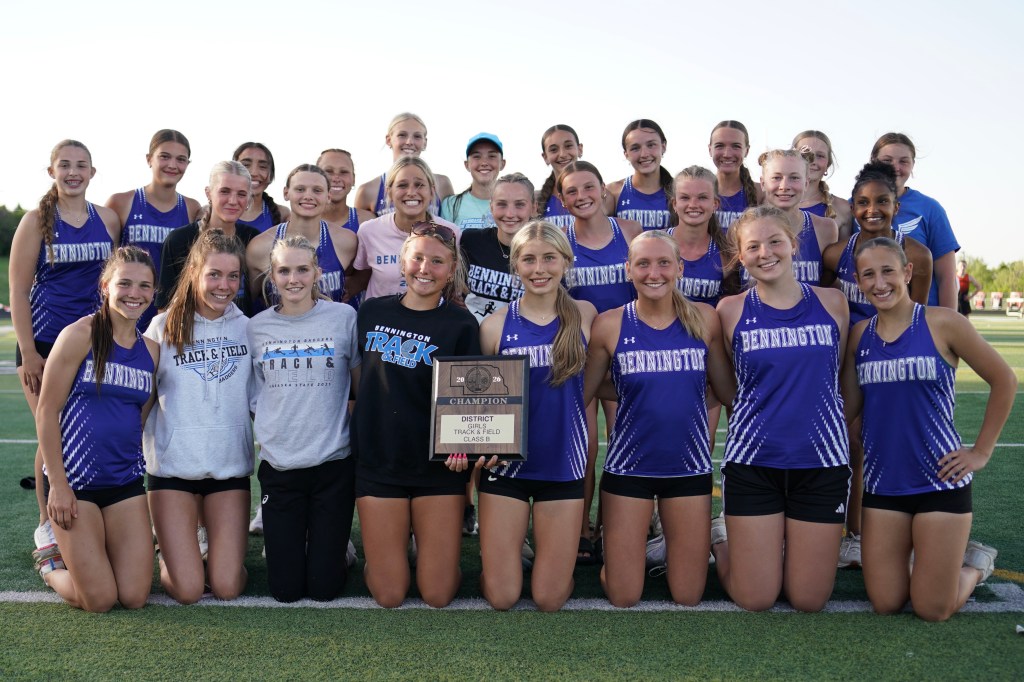 Group photo of the Bennington track and field team celebrating with a championship plaque after winning a district competition.