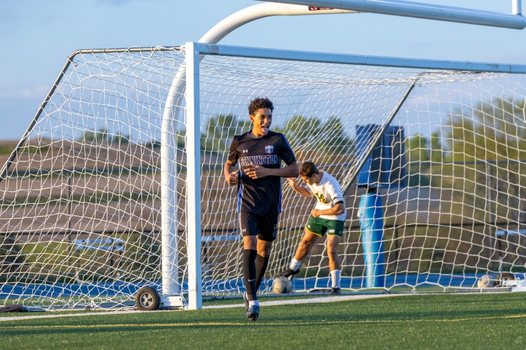 A soccer player celebrates a goal on the field, while another player in the background prepares to defend the goal.