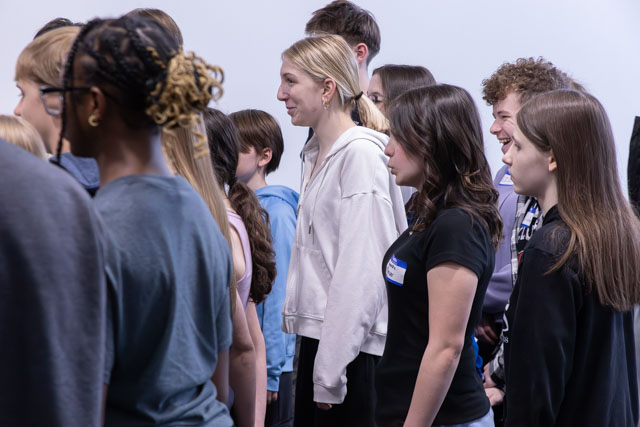A group of young people standing in a line, facing forward, during an event or activity.