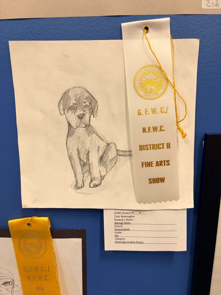A pencil drawing of a seated dog on a white paper, accompanied by a blue ribbon that reads 'G.F.W.C. N.F.W.C. DISTRICT II FINE ARTS SHOW'.