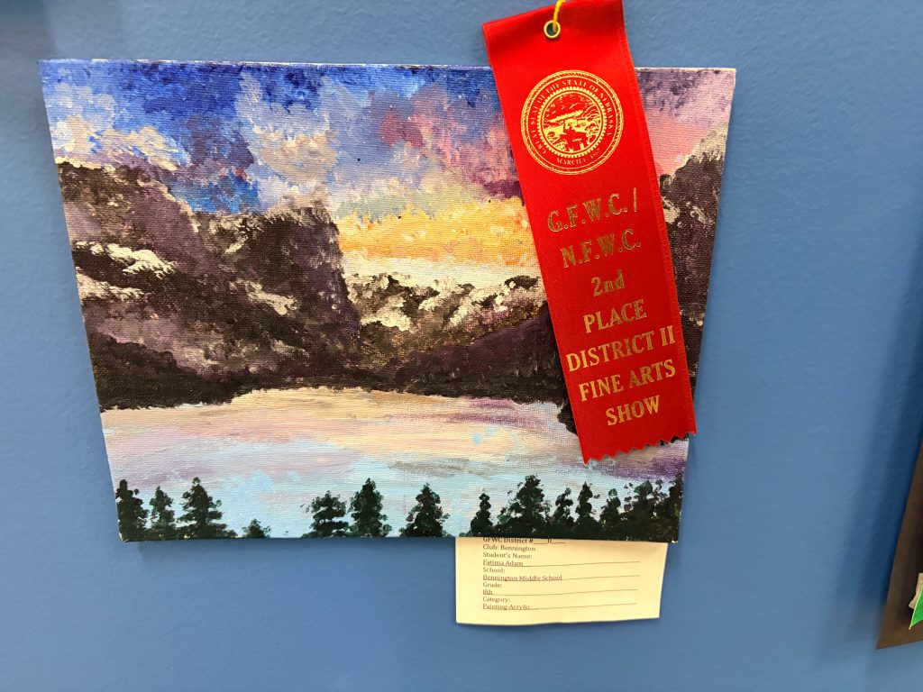 A colorful painting depicting a scenic landscape with mountains and a lake, featuring a red ribbon indicating 2nd place in a fine arts show.