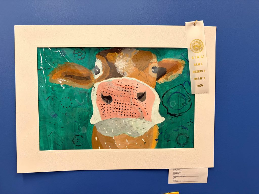 A colorful, artistic representation of a cow with a green background, framed and displayed. The artwork includes various textures and patterns, showcasing the cow's face prominently.