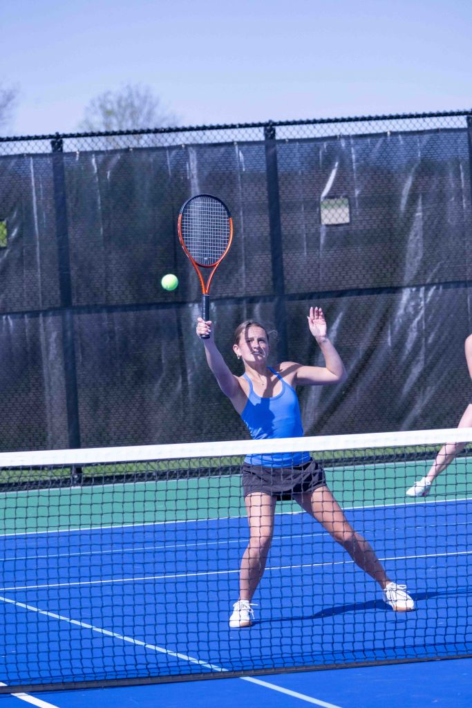 A female tennis player prepares to hit a ball during a match on a blue court.