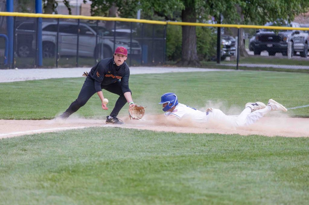 A baseball player sliding into home plate while another player prepares to catch the ball at the base.