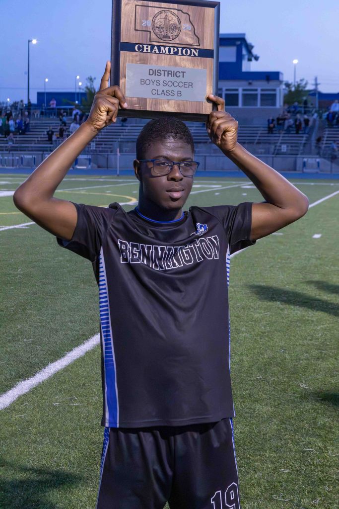 A soccer player holding up a championship plaque, celebrating after winning the district boys soccer class B title.