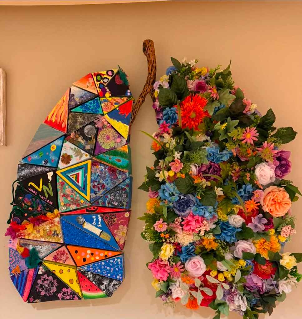 A colorful artistic installation featuring a large triangular mosaic on the left and a vibrant floral arrangement on the right, both mounted on a wall.
