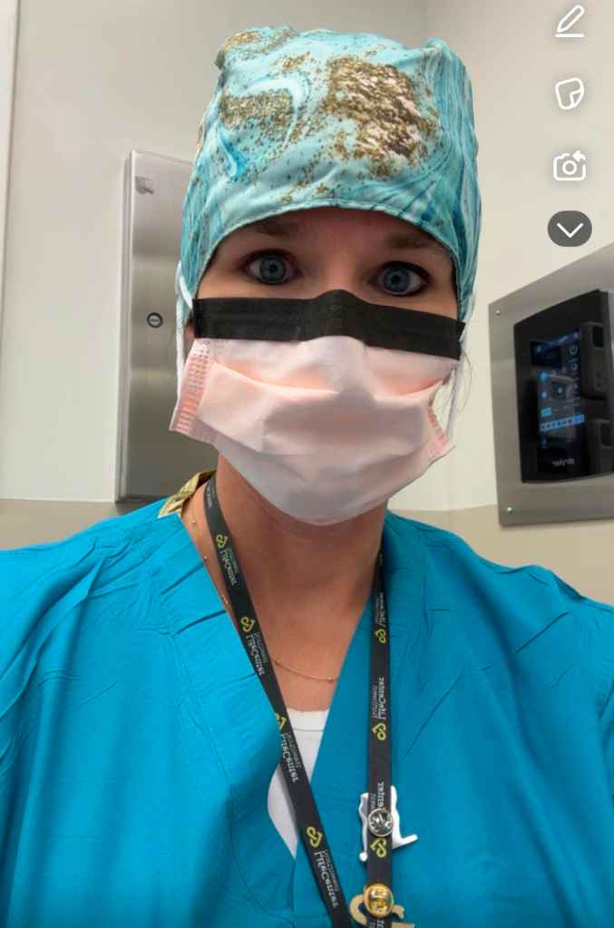 A healthcare professional wearing a colorful surgical cap and a protective mask, looking directly at the camera with a neutral expression in a hospital setting.
