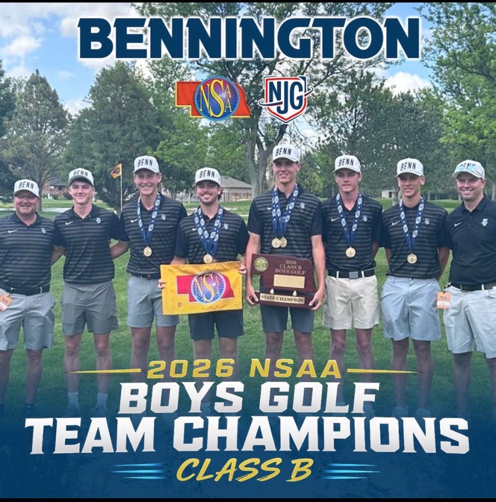 A group of seven male golf players from Bennington, proudly displaying their championship trophy and medals, celebrating their victory as the 2026 NSAA Boys Golf Team Champions in Class B. They are wearing matching black shirts and hats, with a golf course visible in the background.