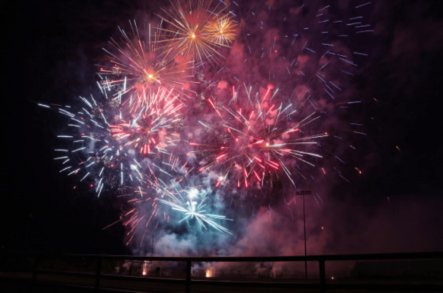 Colorful fireworks bursting in the night sky with clouds of smoke.