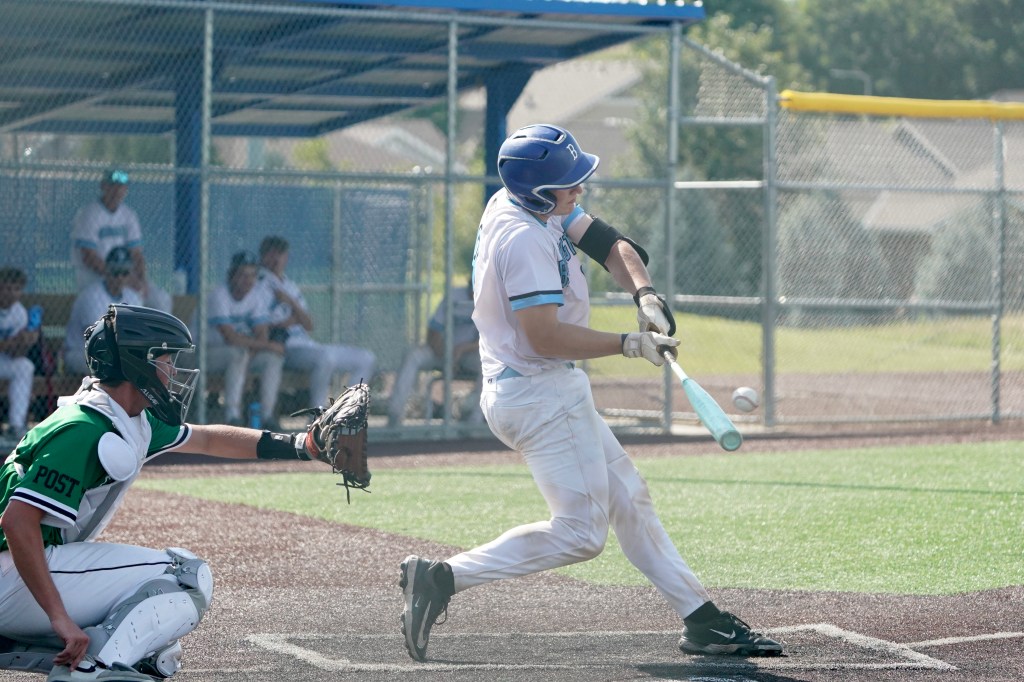 A baseball player is swinging a bat at a pitched ball while a catcher prepares to catch behind the home plate. The player is wearing a white uniform with a blue helmet, and the catcher is in a black and green outfit.