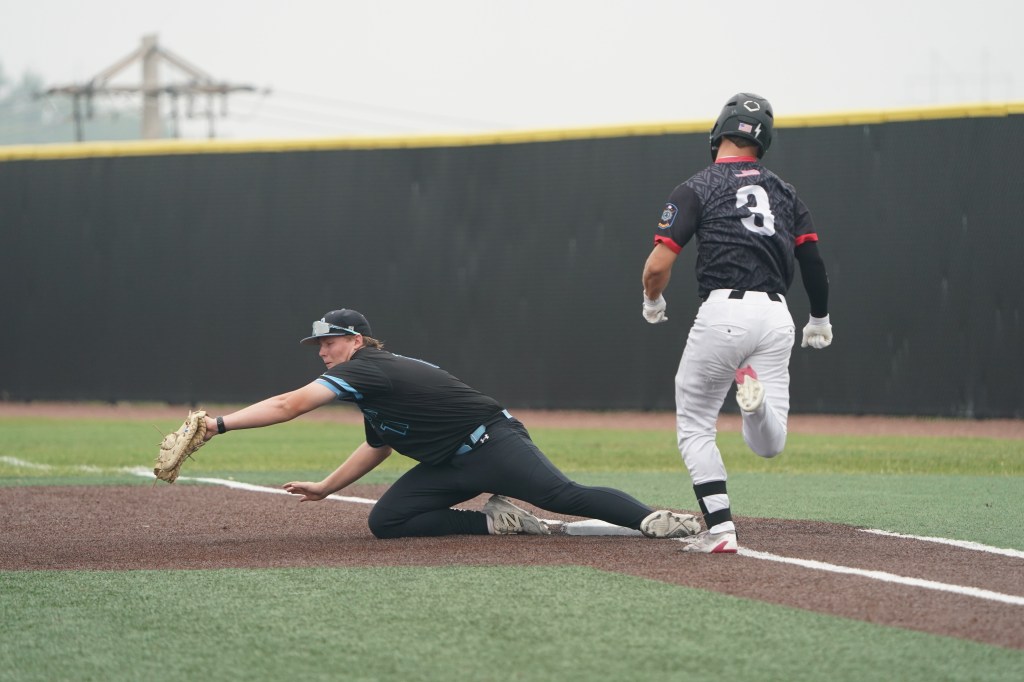 A player sliding into first base while another player stretches to catch a throw in a baseball game.