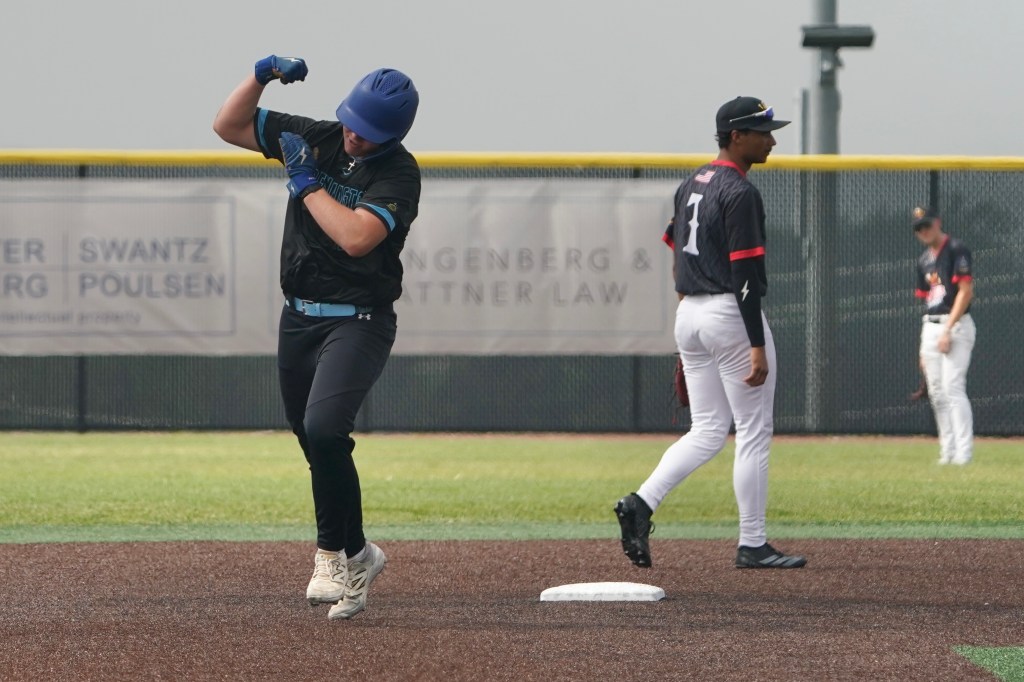 A baseball player celebrates on the field after a play, with clenched fists raised, while another player stands nearby in a black and red uniform.