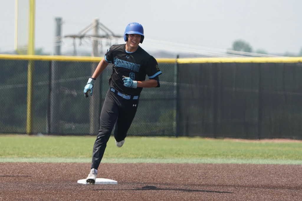 A baseball player running towards first base on a field, wearing a blue helmet and black uniform with 'Bennington' lettering.