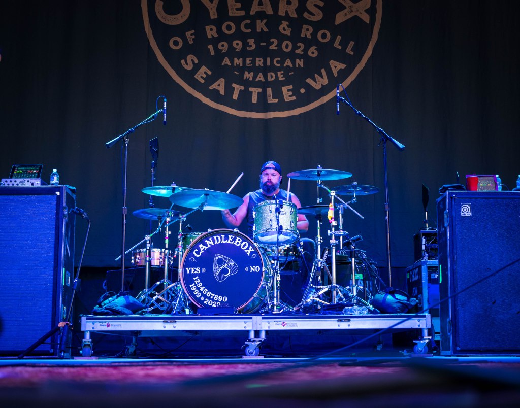 A drummer playing on stage with a black and white drum kit, featuring the band logo 'Candlebox.' The backdrop promotes '30 Years of Rock & Roll' in Seattle.