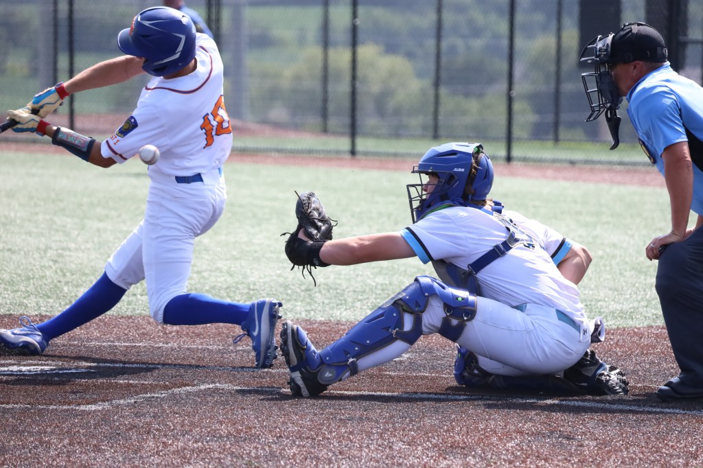 A baseball player swings at a pitch while the catcher prepares to receive the ball, with an umpire observing the play.