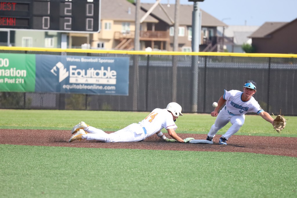 A baseball player sliding into a base while another player reaches out to tag him, set on a sunny day at a baseball field.