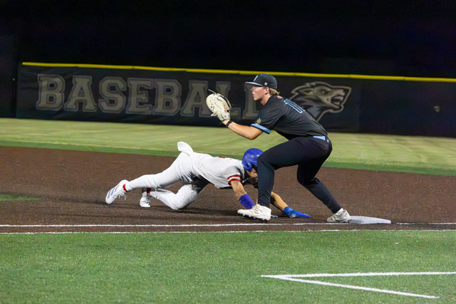 A baseball player diving to reach a base while another player prepares to tag him out.