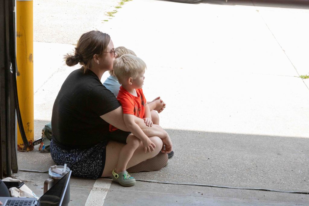 A woman sitting on the ground with two young children, watching the outside scenery.