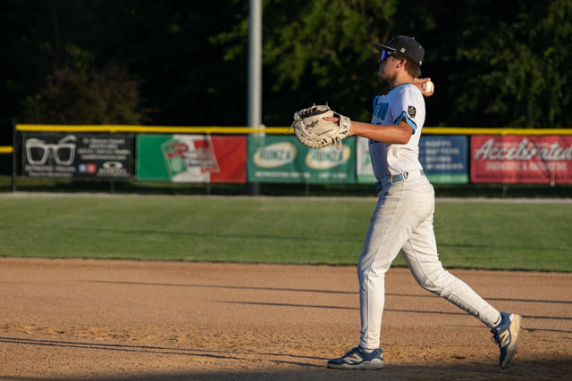 Baseball player in white uniform throwing a ball from the infield during a game.