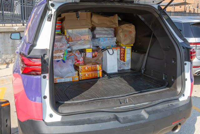 The open trunk of an SUV filled with boxes and bags of food and supplies.