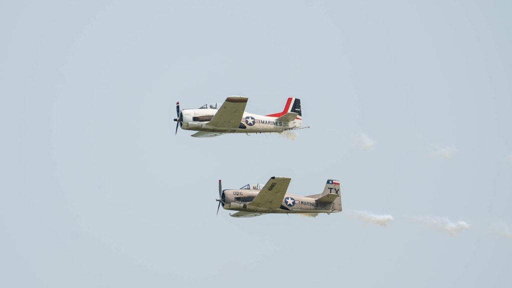 Two military aircraft performing a synchronized flight maneuver against a clear sky.