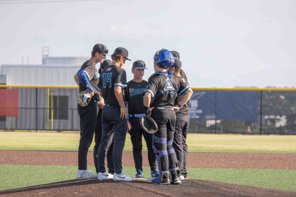 A group of young baseball players huddled together on the pitcher's mound, discussing strategy during a game.