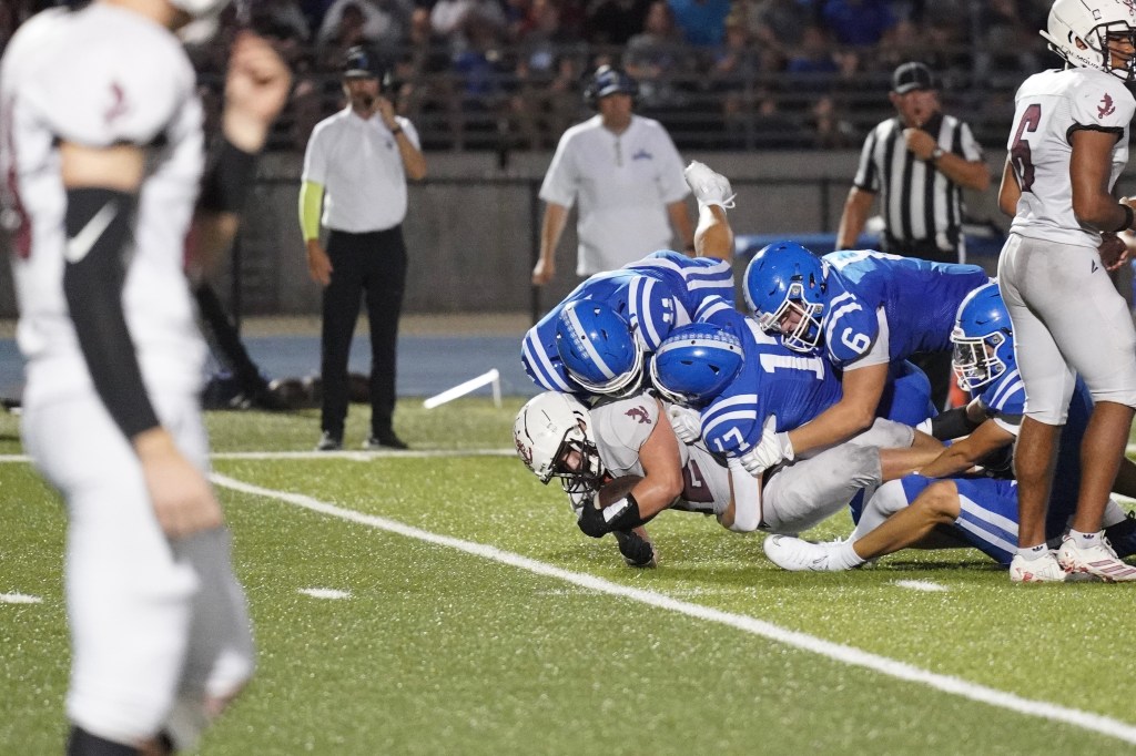 A football player is tackled on the field by multiple opposing players during a game.