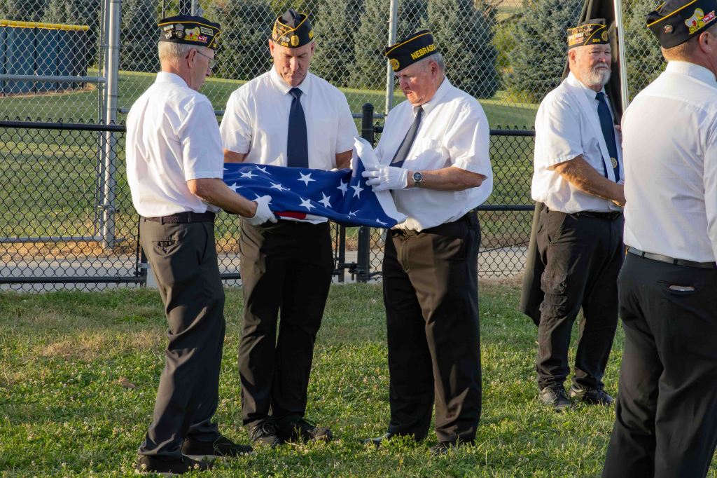 A group of veterans in uniform carefully folding an American flag during a ceremonial event.